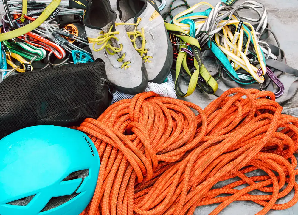 A modern climbing harness and helmet resting on a rock